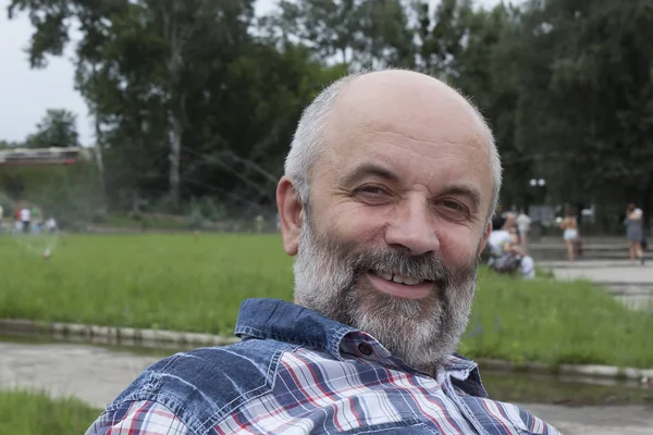 A man of mature age, bald with a beard, in a plaid shirt close-u — Stock Photo, Image