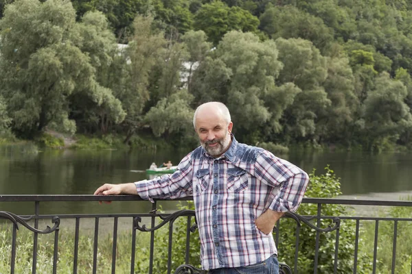 A man of mature age, bald with a beard, in a plaid shirt on the — Stock Photo, Image