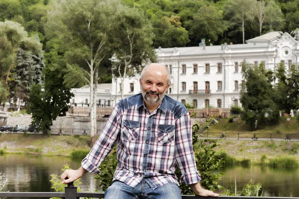 A man of mature age, bald with a beard, in a plaid shirt on the — Stock Photo, Image