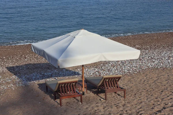 Two sunbeds and umbrella with small table — Stock Photo, Image