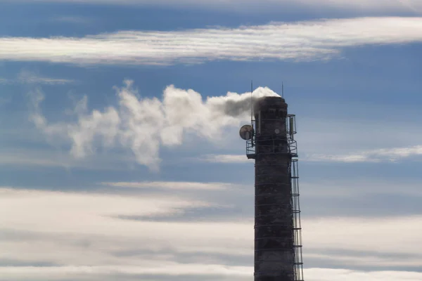 Chaminé, elevando-se contra o céu azul com nuvens — Fotografia de Stock