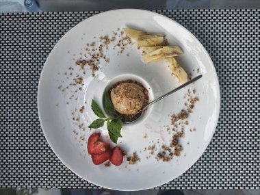 Çilekli ve muzlu karamelli dondurma topu. Nane yapraklarıyla süslenmiş..