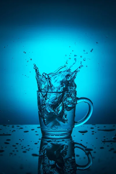 Splash of water in a cup on a blue background.