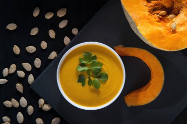 Balkabağı çorbası ve kabak çekirdeği bir siyah ahşap tablo.