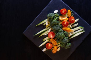 Salatalık, domates ve brokoli karanlık mazisi bir siyah ahşap tablo üzerinde sebze salatası. En baştan görüntülemek.