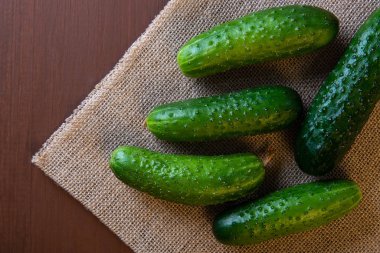 Salatalık üzerinde ahşap bir masa üzerinde çuval bezi.