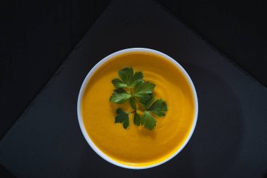 Siyah ahşap bir masada balkabağı çorbası.