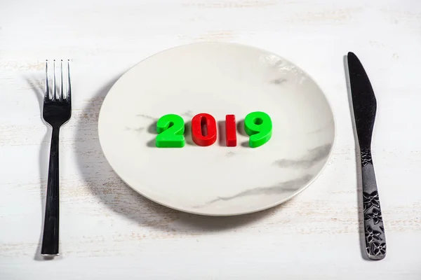 Christmas background with a plate and numbers 2019 on a wooden table.