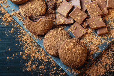 Çikolatalı kurabiye, parça çikolata ve kakao tozu bir ahşap arka plan üzerinde kırık