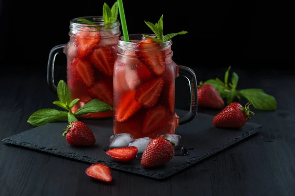 Färsk jordgubbs smoothie. Fräsch sommar cocktail med jordgubbar och isbitar på en mörk bakgrund på ett svart träbord. — Stockfoto