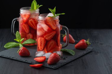 Taze çilekli smoothie. Siyah ahşap bir masa üzerinde koyu bir arka plan üzerinde çilek ve buz küpleri ile taze yaz kokteyli.