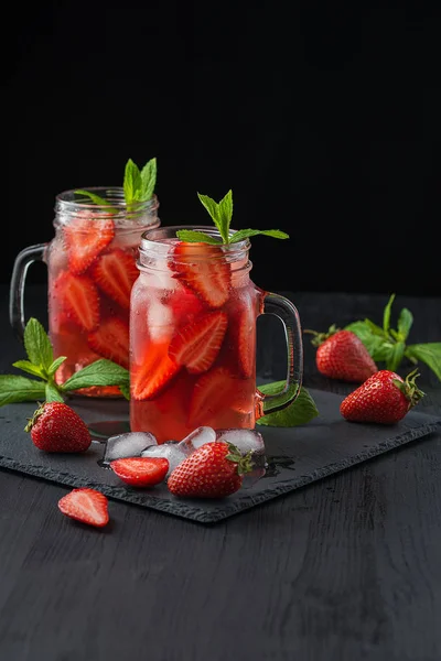 Batido de fresa fresca. Cóctel fresco de verano con fresas y cubitos de hielo sobre un fondo oscuro sobre una mesa de madera negra . —  Fotos de Stock