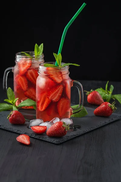 Batido de fresa fresca. Cóctel fresco de verano con fresas y cubitos de hielo sobre un fondo oscuro sobre una mesa de madera negra . —  Fotos de Stock