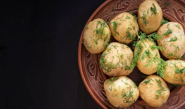 Vařené brambory s Dill v plechu na černém dřevěném stole. — Stock fotografie