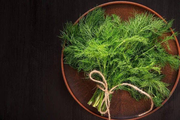 Fresh dill in a plate on a wooden black table. — Stock Photo, Image