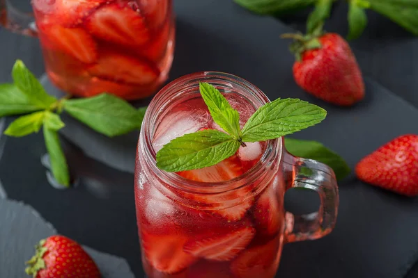 Färsk jordgubbs smoothie. Fräsch sommar cocktail med jordgubbar och isbitar på en mörk bakgrund på ett svart träbord. — Stockfoto