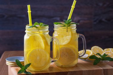 Siyah ahşap bir masada buzlu ve naneli bir kavanozda limonata.