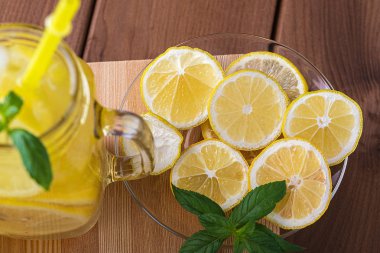 Cam bir tabakta limon dilimleri ve tahta bir masada limonata.