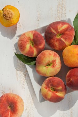 Beyaz ahşap arka plan üzerinde bir tabakta taze olgun şeftali. Taze meyve arka plan. Yaz meyveleri.