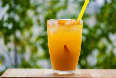 Yeşil arka planda şeftali kokteyli veya buzlu çay.