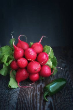 Ay ışığında tahta bir masada turp ve yeşil biber.