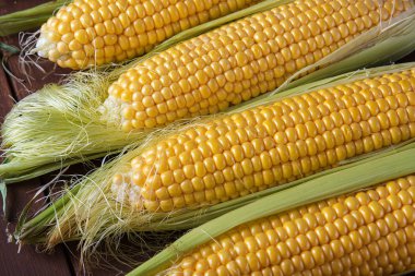 Kahverengi ahşap masadaki koçandaki taze mısır.