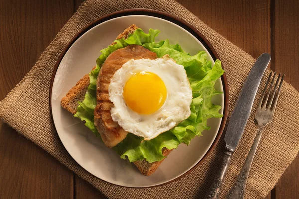 Œuf frit et poulet sur pain pour le petit déjeuner sur assiette et table rustique — Photo