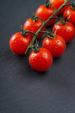 Siyah arka planda taze kiraz domatesleri. Kopyalama alanı olan yan görünüm.