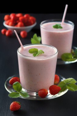 Çilekli smoothie ya da siyah kırsal arka planda cam bardakta milkshake kahvaltı ve atıştırmalık sağlıklı yiyecekler.