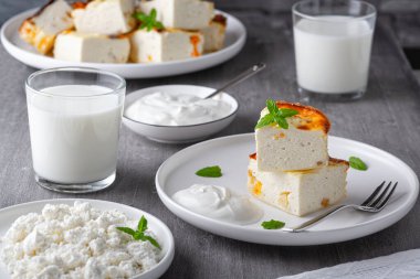 Üzümlü süzme peynir güveci ve tahta gri arka planda bir fincan süt. Süzme peynir güveci.