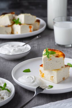  Üzümlü süzme peynir güveci ve tahta gri arka planda bir fincan süt. Süzme peynir güveci..