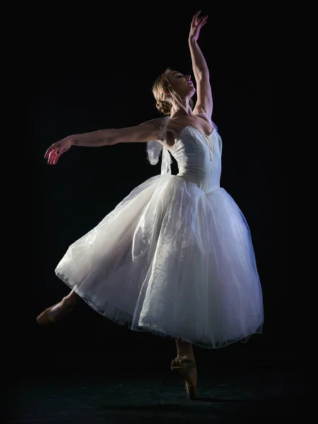Gracieuze ballerina in witte tutu jurk elementen van klassieke of moderne ballet dansen in het donker met de neon licht en rook op de zwarte achtergrond. kunst concept. — Stockfoto