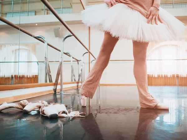Ballerina in het ballet pointe en witte tutu strekt zich uit over barre in sportschool. Vrouw in dansstudio te beoefenen. Uit het werk van jonge meisje. — Stockfoto