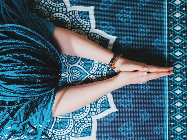 Skoncentrowany kobieta z niebieski afrykańskie Warkoczyki, modląc się z mala drewniana różańca. Namaste. Zbliżenie dłoni na matę do jogi z mandali. Widok z góry. — Zdjęcie stockowe
