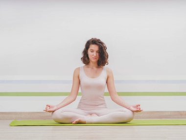 Işık minimalist stüdyo sınıf oda yoga pratik genç güzel kadın. Çekici kız klasik lotus bulunduğu oturur ve onu meditasyon başlar