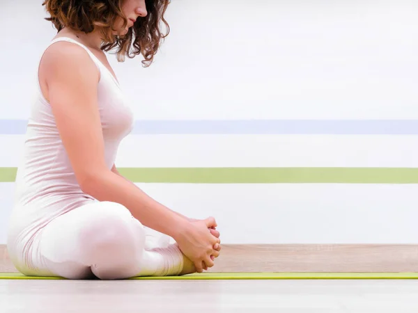 Joven mujer bonita practicando yoga en la sala de clase de estudio minimalista de luz. Chica atractiva se sienta en posición de loto clásico y comienza su meditación — Foto de Stock