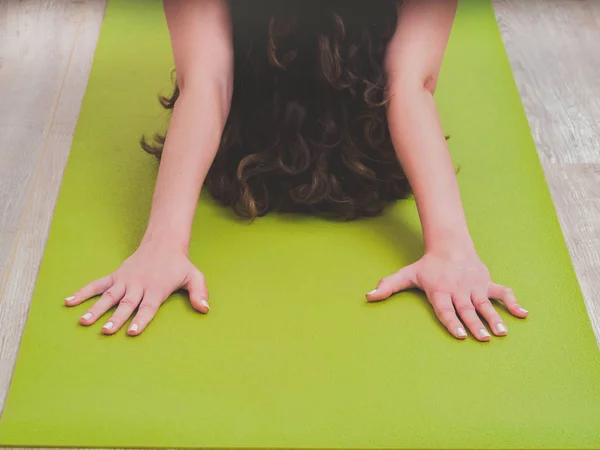 Mujer joven con el pelo rizado haciendo ejercicio de yoga en el gimnasio, la cara no es visible. Concéntrate en las manos . — Foto de Stock