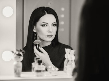 Onun makyaj uygulayarak Bayan yansımasıdır. Esmer olgun kadın aynaya bakarken toz koyarak. Makyaj, gece partiye gitmeden önce hazırlanıyor.