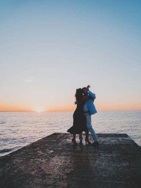 Genç İspanyol çift günbatımı deniz bir arka plana dayanır. Küçük tesisi Avrupa şehri. Erkek ve kadın latin Amerika şehvetli dans dans: bachata, salsa veya kizomba.