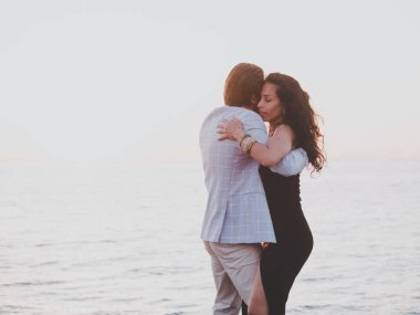 Genç İspanyol çift günbatımı deniz bir arka plana dayanır. Küçük tesisi Avrupa şehri. Erkek ve kadın latin Amerika şehvetli dans dans: bachata, salsa veya kizomba.