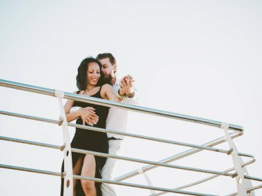 Genç İspanyol çift günbatımı deniz bir arka plana dayanır. Küçük tesisi Avrupa şehri. Erkek ve kadın latin Amerika şehvetli dans dans: bachata, salsa veya kizomba.