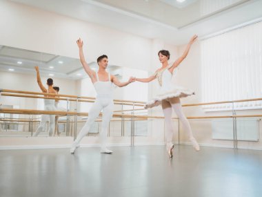 Eğitim performans önce. O spor salonu ya da bale salonunda beyaz tutu giysili güzel kadına döner klasik bale dans adam. Çift şehvetli dans gerçekleştirin. Minimalizm iç.