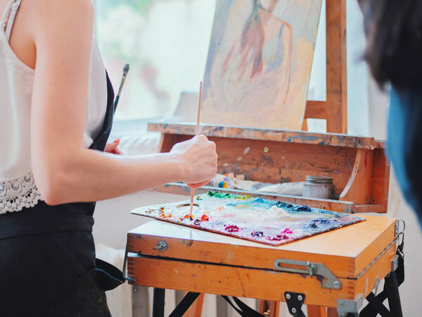 Wooden art palette with oil paints. Mixing colors together. Artistic instrument with many colors. Working tool with squeezed out tubes of paint.