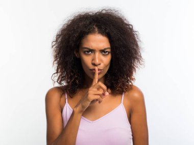 Bir parmak onun dudaklarında beyaz arka plan üzerinde tutan Afrikalı-Amerikalı kadın. Şşşt gizli jest.