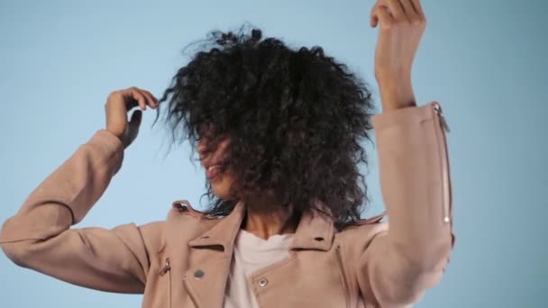 아름 다운 혹 백 혼혈 아 혼혈 여자 헤어스타일 머리 웃 고 파란색 배경 위에 스튜디오에서 춤을 재미와 핑크 패션 재킷. 유행 hipster 아프리카 소녀입니다. 슬로우 모션 — 비디오