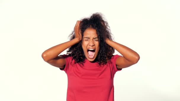 Uma afro-americana a gritar em cima de vermelho a tapar os ouvidos com olhos fechados. Deprimido irritado preto menina sobre branco fundo no estúdio . — Vídeo de Stock
