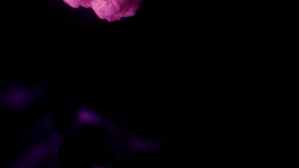 Encre rose pailletée dans l'eau créant un nuage abstrait — Video