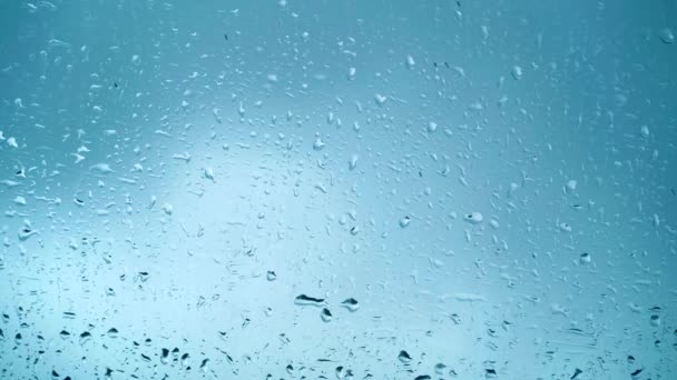 Vista de perto de gotas de água caindo em vidro. Chuva correndo na janela. Temporada chuvosa, outono. Gotas de chuva caem, céu cinzento. Ótimo para efeitos especiais e gráficos de movimento — Vídeo de Stock