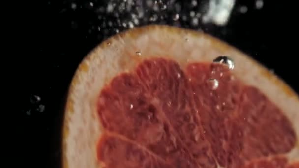 Свіжий грейпфрут занурюється у воду, повільний рух — стокове відео