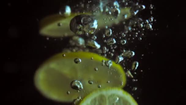Свежие ломтики лимона, погружающиеся в воду, замедленная съемка — стоковое видео